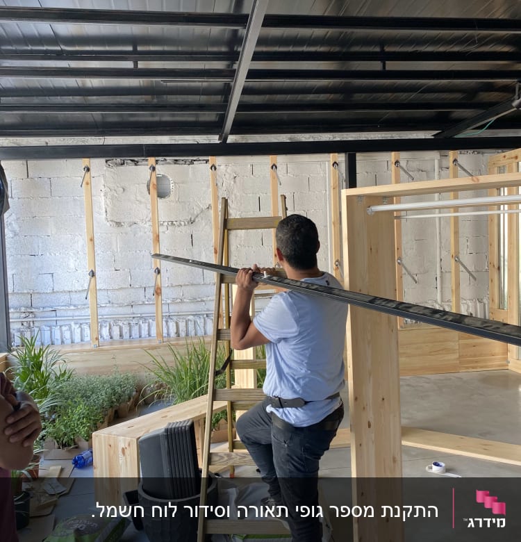 חשמלאי עובד על תקרה עם סולם וכלים